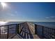 Scenic view of a long wooden pier stretching into the calm, sunlit waters under a clear blue sky at 803 Oak Bend Ln, Dunedin, FL 34698