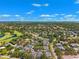 Wide aerial view showcasing a sprawling residential area with lush green trees, a golf course, and a serene lake at 8645 Piper Ln, Seminole, FL 33777