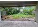 Overgrown backyard with unkempt foliage as viewed from under a covered patio at 8645 Piper Ln, Seminole, FL 33777