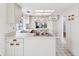 Open kitchen with bright lighting featuring white cabinets and countertops, skylight, and view to living space at 8645 Piper Ln, Seminole, FL 33777