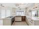 Bright kitchen with white cabinetry, tile floors, and ample natural light from a window and skylight at 8645 Piper Ln, Seminole, FL 33777