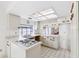 Bright kitchen featuring white cabinetry, ample counter space, and a convenient pass-through to another room at 8645 Piper Ln, Seminole, FL 33777