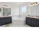 Bathroom featuring double sink vanities, a soaking tub, and neutral decor at 9508 Pyrenees Pl, Seffner, FL 33584