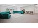 Spacious bonus room featuring plush carpet, a game table and a large teal wrap around sofa for entertaining at 9508 Pyrenees Pl, Seffner, FL 33584
