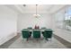 The dining room showcases a modern chandelier, contemporary decor, and stylish, comfortable green chairs at 9508 Pyrenees Pl, Seffner, FL 33584