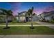 Charming home featuring landscaped lawn and garden, with palm trees, enhanced by a beautiful sunset sky at 978 Signet Dr, Apollo Beach, FL 33572