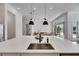 Modern kitchen with a large island, stainless steel sink, and sleek black pendant lighting overlooking the living area at 978 Signet Dr, Apollo Beach, FL 33572