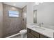 Modern bathroom with gray tiled walls, a glass shower, and single sink vanity at 10115 Briar Cir, Hudson, FL 34667
