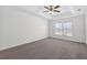 Bright bedroom featuring a ceiling fan, tray ceiling, plush carpet, and a large window at 10115 Briar Cir, Hudson, FL 34667