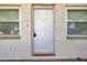 Classic white front door flanked by windows framed by light brick at 10125 Cherry Creek Ln, Port Richey, FL 34668