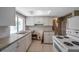 Open kitchen featuring white cabinets, a skylight, a double sink, and white appliances at 10125 Cherry Creek Ln, Port Richey, FL 34668