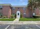 Inviting red brick building with a manicured lawn, enhanced by a lush palm tree at 1125 83Rd N Ave # D, St Petersburg, FL 33702