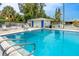 Another angle of the community pool with a lifeguard ring and amenities, surrounded by mature trees and greenery at 12400 Park Blvd # 417, Seminole, FL 33772
