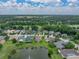 Areal view featuring a home near a serene pond and lush green surroundings, showcasing a picturesque neighborhood at 12413 Woodlands Cir, Dade City, FL 33525
