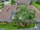Aerial view of a backyard with a screened-in lanai, lush green grass, and palm trees at 12413 Woodlands Cir, Dade City, FL 33525