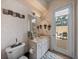 Bathroom with white vanity, toilet, patterned wallpaper, and sliding glass door at 12413 Woodlands Cir, Dade City, FL 33525
