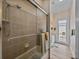 Bathroom with tiled shower, glass door, and neutral walls and floors at 12413 Woodlands Cir, Dade City, FL 33525