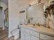Bathroom with white vanity, toilet, patterned wallpaper, and tiled shower at 12413 Woodlands Cir, Dade City, FL 33525