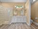 Bright bathroom featuring a walk-in shower, dual sinks, and ample counter space at 12413 Woodlands Cir, Dade City, FL 33525