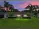 Charming home with manicured lawn, landscape lighting, and symmetrical palm trees at 12413 Woodlands Cir, Dade City, FL 33525