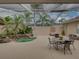 A relaxing screened lanai features a spa, outdoor dining area, and lush tropical plants at 12413 Woodlands Cir, Dade City, FL 33525
