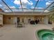 A screened lanai offers a tranquil spa, outdoor dining area, and views of the landscaped yard at 12413 Woodlands Cir, Dade City, FL 33525