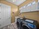 Laundry room with gray front load washer and dryer, white cabinets, and tan walls at 12413 Woodlands Cir, Dade City, FL 33525