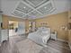 Luxurious primary bedroom with coffered ceiling, wood floors, and seamless access to outdoor living at 12413 Woodlands Cir, Dade City, FL 33525