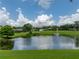 Scenic view of a community pond with a fountain, surrounded by lush greenery at 12413 Woodlands Cir, Dade City, FL 33525