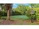 Community basketball court with green surface and a black metal fence with lush landscaping and trees at 1313 Oxbridge Dr, Lutz, FL 33549