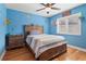 A blue-themed bedroom with a ceiling fan, hardwood floors, and a window with blinds at 1313 Oxbridge Dr, Lutz, FL 33549