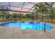 Inviting screened-in pool and spa with stone deck, overlooking a large yard and picturesque lake view at 1313 Oxbridge Dr, Lutz, FL 33549