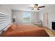 Bright bedroom with wooden floors, ceiling fan, white headboard, and large window at 1655 Blue Rose Dr, Ruskin, FL 33570