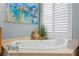 Close up of tub featuring neutral tile and shutters for natural light at 17921 Arbor Haven Dr, Tampa, FL 33647
