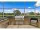 Outdoor kitchen featuring stone countertops, stainless steel appliances and views of the pond from the lanai at 17921 Arbor Haven Dr, Tampa, FL 33647