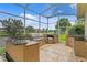 Outdoor kitchen with stone countertops, stainless appliances, and a scenic view of the pond from the enclosed lanai at 17921 Arbor Haven Dr, Tampa, FL 33647