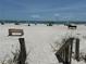View of the white sandy beach with beach benches and beachgoers enjoying the sun at 19451 Gulf Blvd # 205, Indian Shores, FL 33785