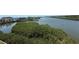 An aerial view showcasing lush mangroves and a tranquil waterfront setting with buildings in the background at 19451 Gulf Blvd # 205, Indian Shores, FL 33785