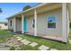 Exterior view with a charming blue door, covered entry, and well-kept landscaping at 21536 Holdern Ave, Port Charlotte, FL 33952