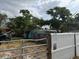 View of the side of a light blue house with mature trees and a metal fence at 2175 20Th Sw Ave, Largo, FL 33774