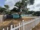 View of the front yard with a white picket fence and mature tree providing shade at 2175 20Th Sw Ave, Largo, FL 33774