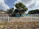 View of the front yard with a white picket fence and mature tree providing shade at 2175 20Th Sw Ave, Largo, FL 33774