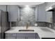 Close up of kitchen sink, marbled backsplash, grey cabinets and gold hardware at 2425 Wishing Well Cir, Tampa, FL 33619