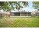 Spacious backyard featuring a screened lanai, lush greenery, and a secure wooden fence at 24841 Mary Beth Ct, Land O Lakes, FL 34639