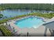 The community pool has lounge seating and umbrellas surrounding it and is next to a pond on a bright day at 2522 Charter Oak Dr, North Port, FL 34289
