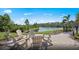 Outdoor seating surrounds a stone patio with a view of the pond and trees in the distance at 2522 Charter Oak Dr, North Port, FL 34289
