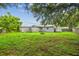 Spacious backyard with lush grass, mature trees, a shed, and a fire pit at 2607 N 59Th St, Tampa, FL 33619