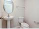 Bathroom with a pedestal sink, oval mirror, white toilet, and towel rack at 3062 Victoria Inlet Dr, Holiday, FL 34691