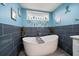 Stylish bathroom showcasing a modern freestanding tub with navy tile accent wall and window at 316 Hillpoint Dr, Palm Harbor, FL 34683