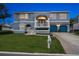 Two-story blue home with a well-manicured lawn, blue garage doors, and a welcoming front porch at twilight at 316 Hillpoint Dr, Palm Harbor, FL 34683